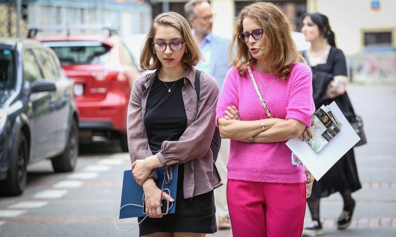 Dwie kobiety w okularach idą po ulicy rozmawiając.